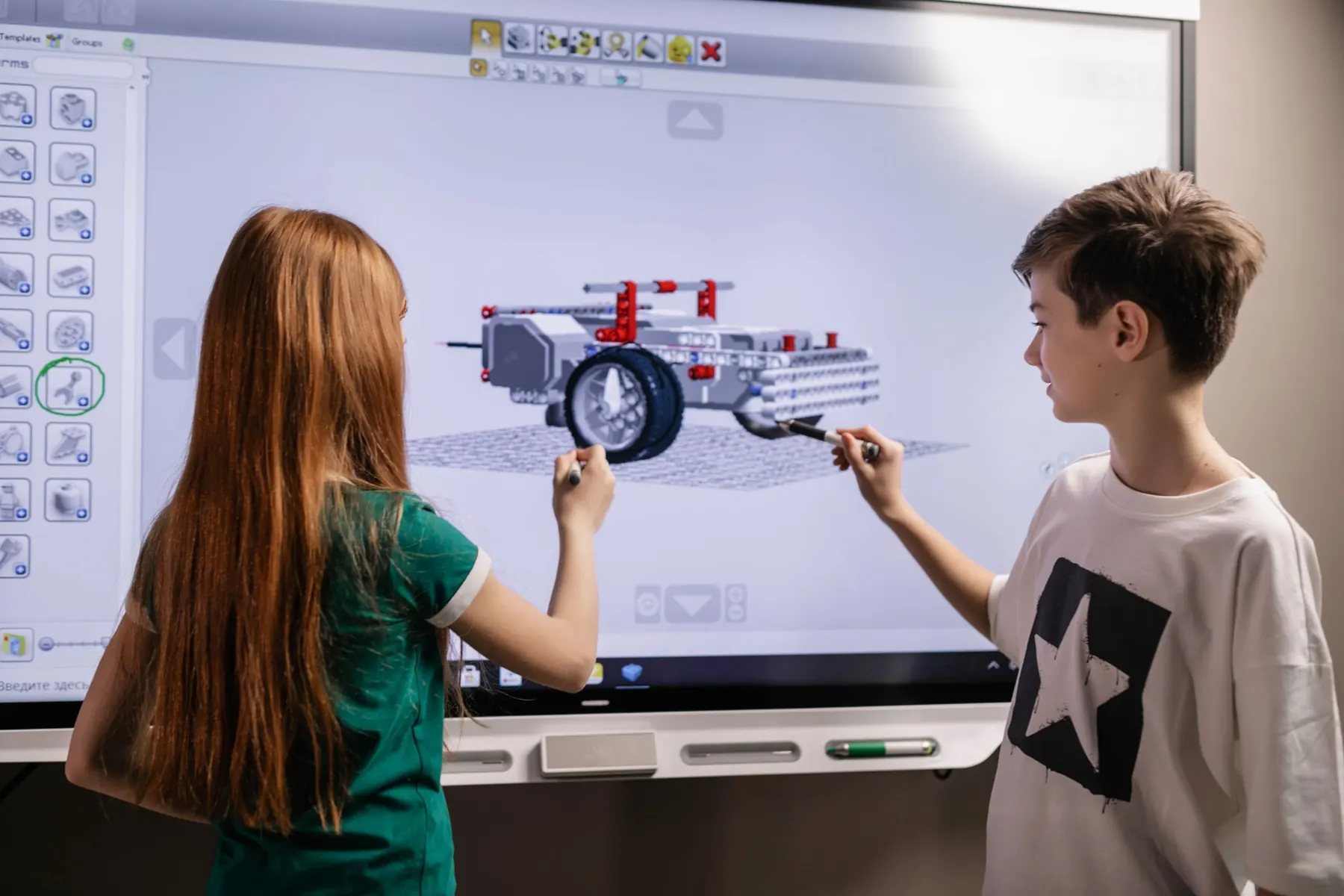 Two students explaining their robot design on an interactive display