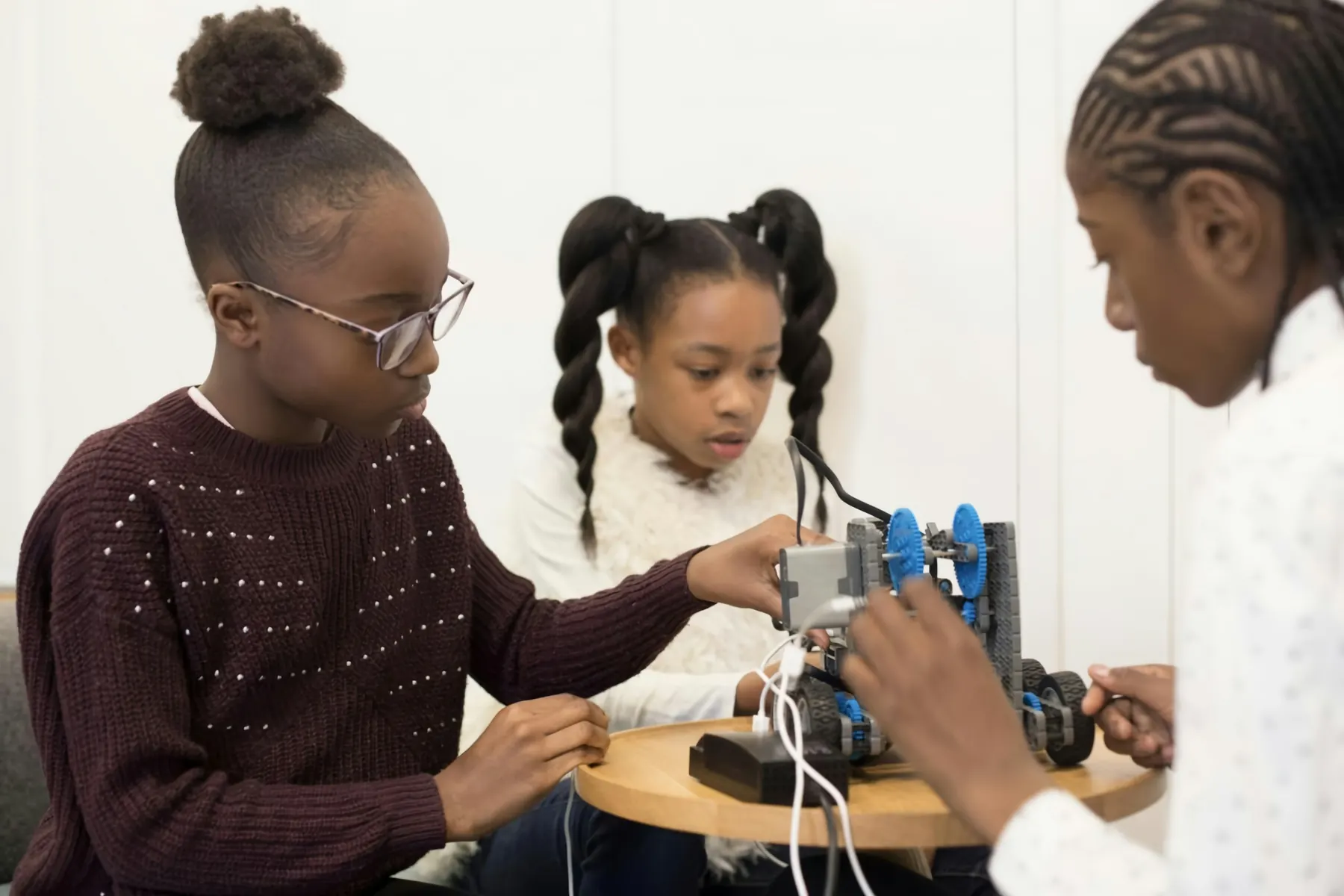 A group of students gathered around a small robot car they are building