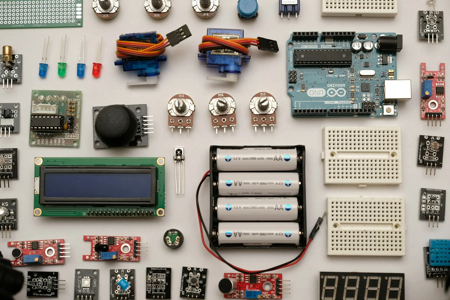 A workbench with an Arduino board, sensors, jumper wires and electronic components